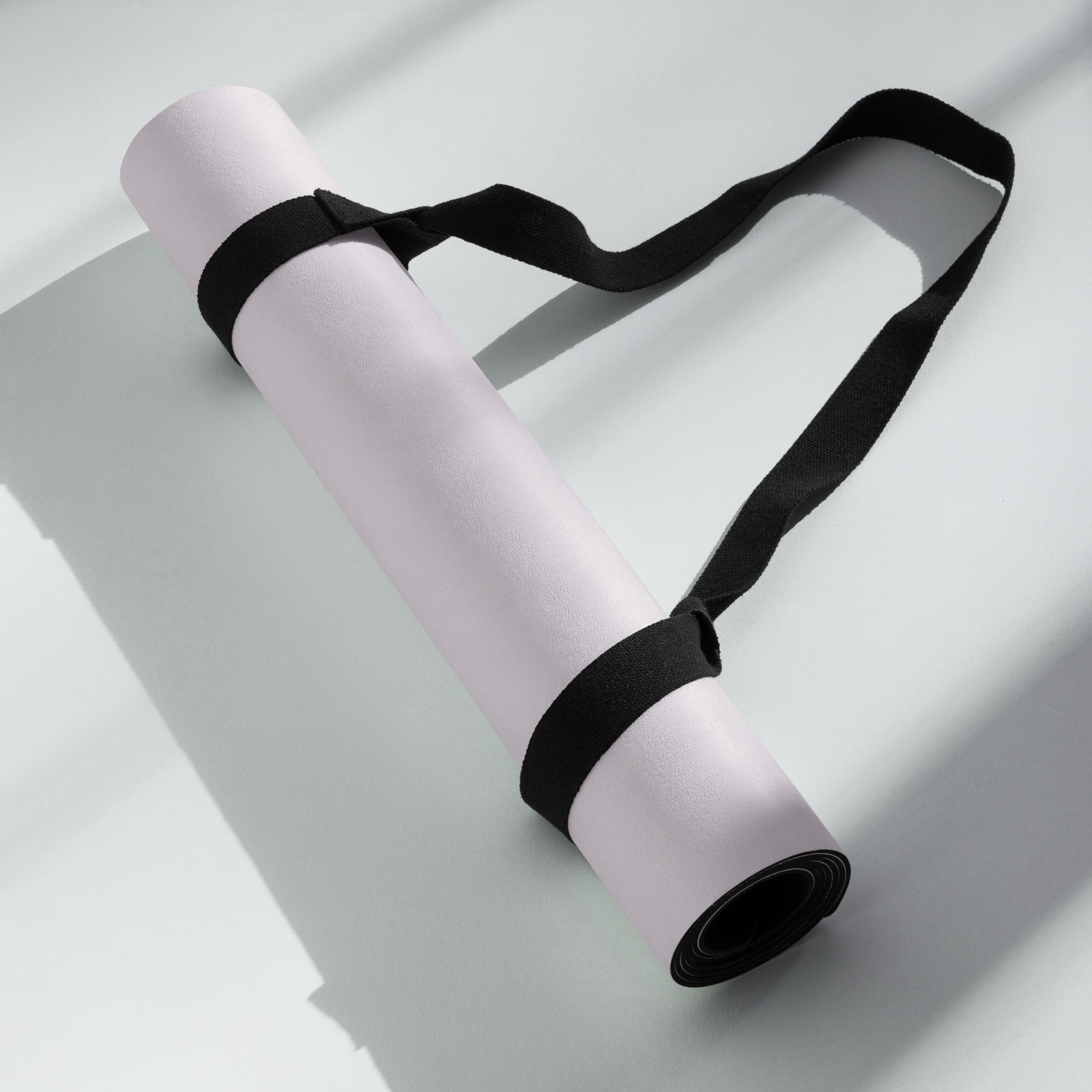 Lavender yoga mat with black carrying strap folded and tied