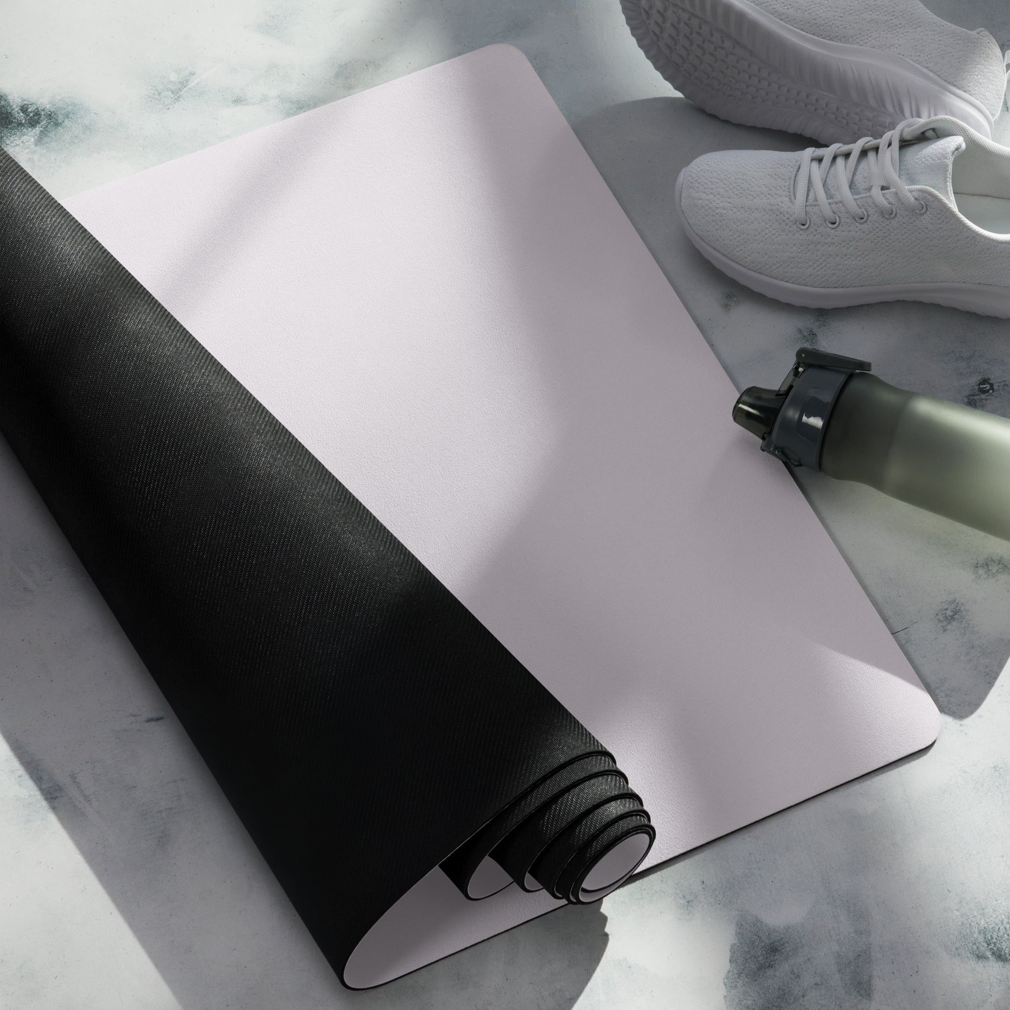 Lavender yoga mat unrolled with black underside and adjacent water bottle