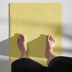Yellow yoga mat with visible rubber texture, feet resting on surface.