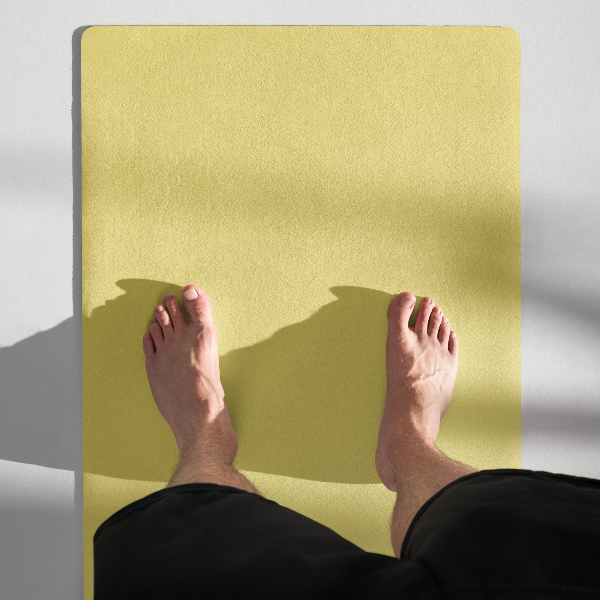 Yellow yoga mat with visible rubber texture, feet resting on surface.