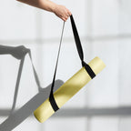 Yellow yoga mat being carried with a black strap held upward.