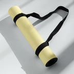 Yellow yoga mat with black carrying strap laid out flat.