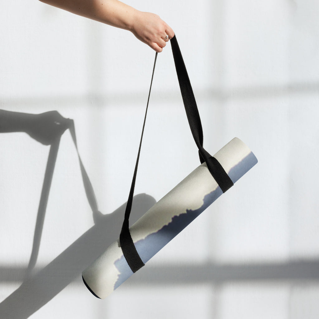 Yoga mat carried with a black strap; blue mountain haze print visible.