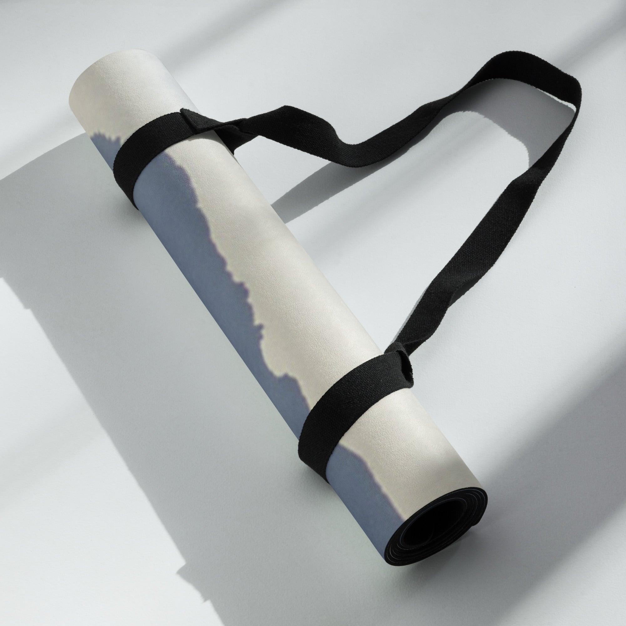 Rolled yoga mat with black carrying strap; blue mountain haze print showing.