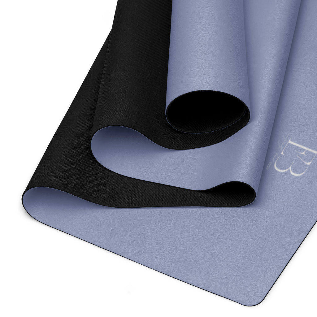 Pale iris yoga mat folded, showing black textured outer layer and rolled center.