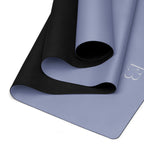 Pale iris yoga mat folded, showing black textured outer layer and rolled center.