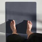 Slate blue yoga mat with embossed logo, used for seated stretch