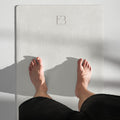 Cream yoga mat with EB logo, hands and feet resting during stretching