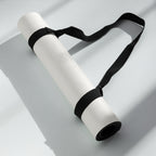 Cream yoga mat rolled with black carry strap tied around the roll