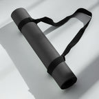 Black yoga mat rolled with black carry strap, folded for compact storage.