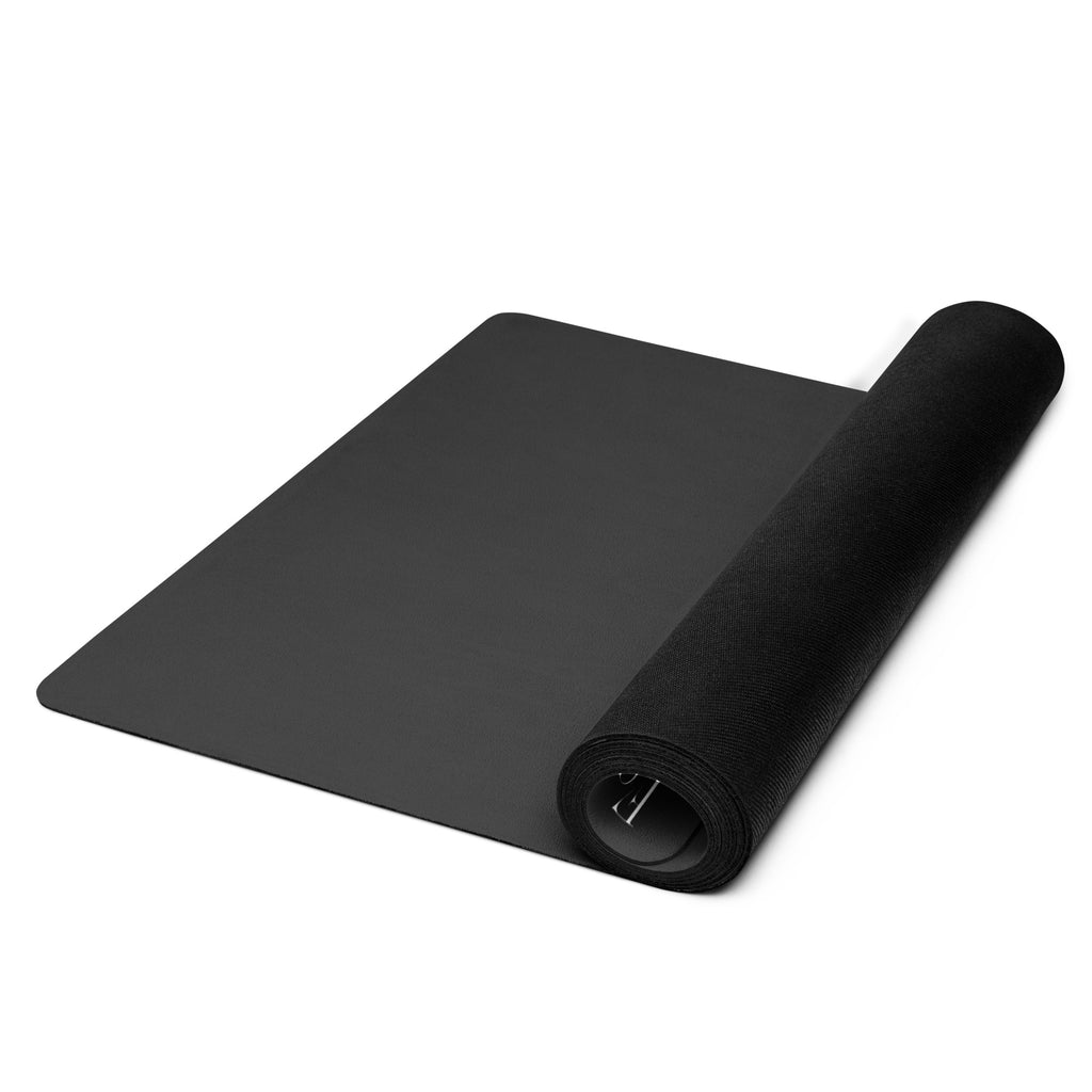 Black yoga mat unrolled with rolled end curling up, showing thickness and edge.