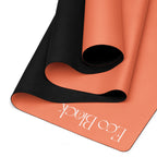 Orange yoga mat with black textured traction underside and embossed brand text near edge.