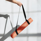 Orange yoga mat rolled and carried with a black strap and end rolled section.