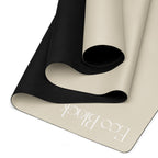 Yoga mat with bone beige base and black top layer, rolled to show inner curve.