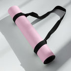 Rolled pink yoga mat secured with black carrying strap band