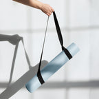 Natural rubber yoga mat in powder blue held with black carry strap.