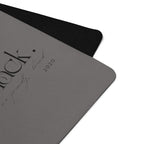 Close-up of black yoga mat corner with textured surface and embossed logo mark.