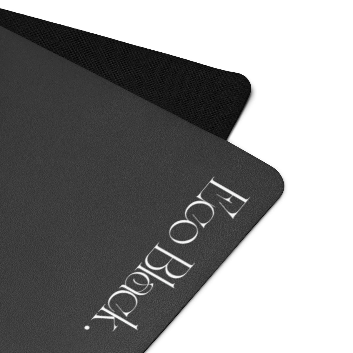 Black yoga mat close-up with Eco Block logo printed on the textured surface.