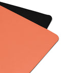 Orange yoga mat with a black textured edge along the corner seam.